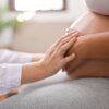 Side view of a doctor touching a pregnant woman's belly