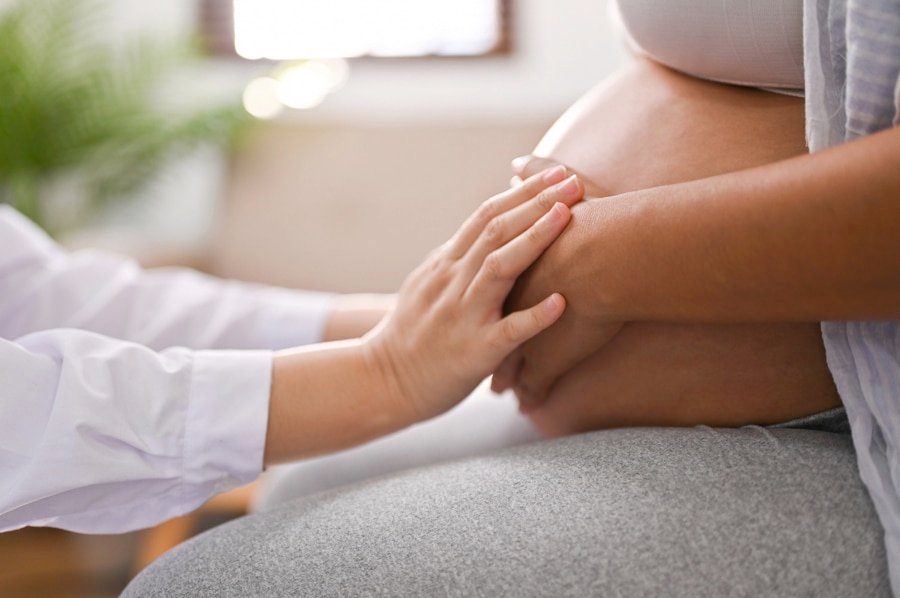 Side view of a doctor touching a pregnant woman's belly