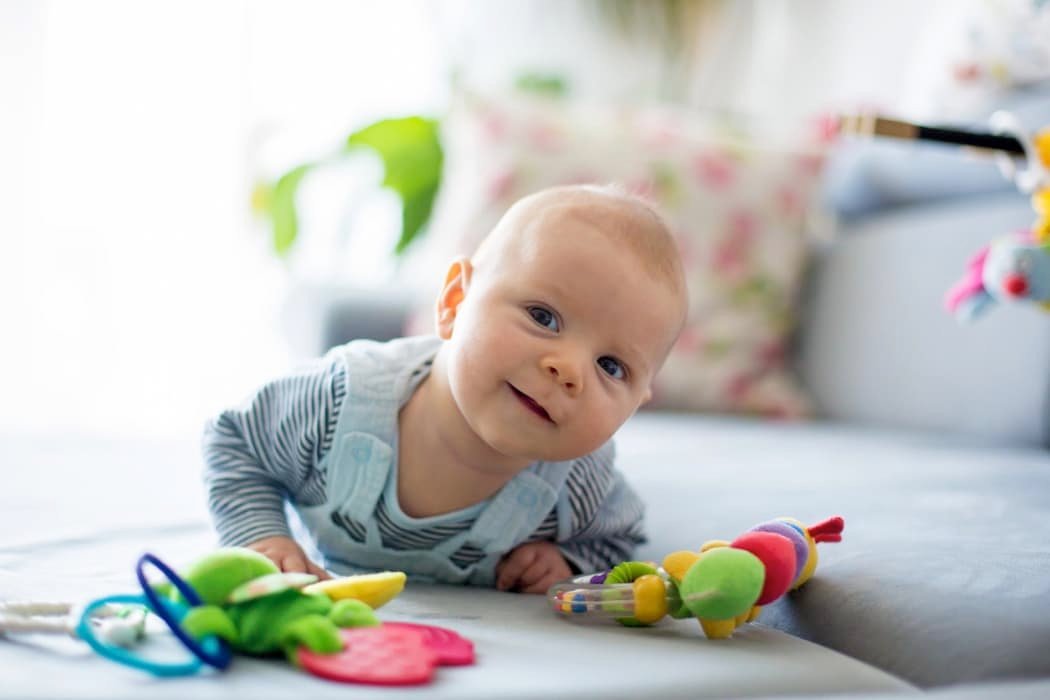 Cute baby boy playing with toys in a living room
