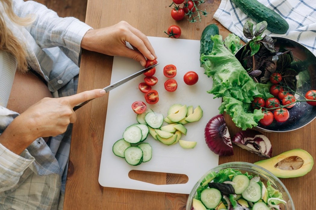 pregnant woman chopping vegetables for meal