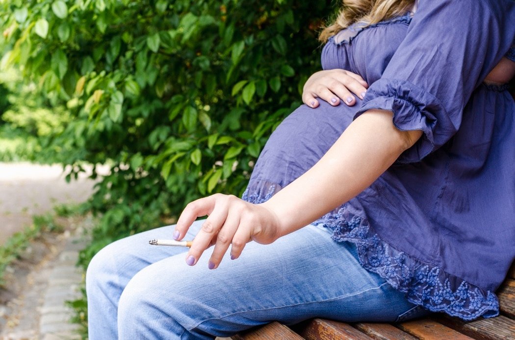 Pregnant Woman Smoking Cigarette Outdoor in park