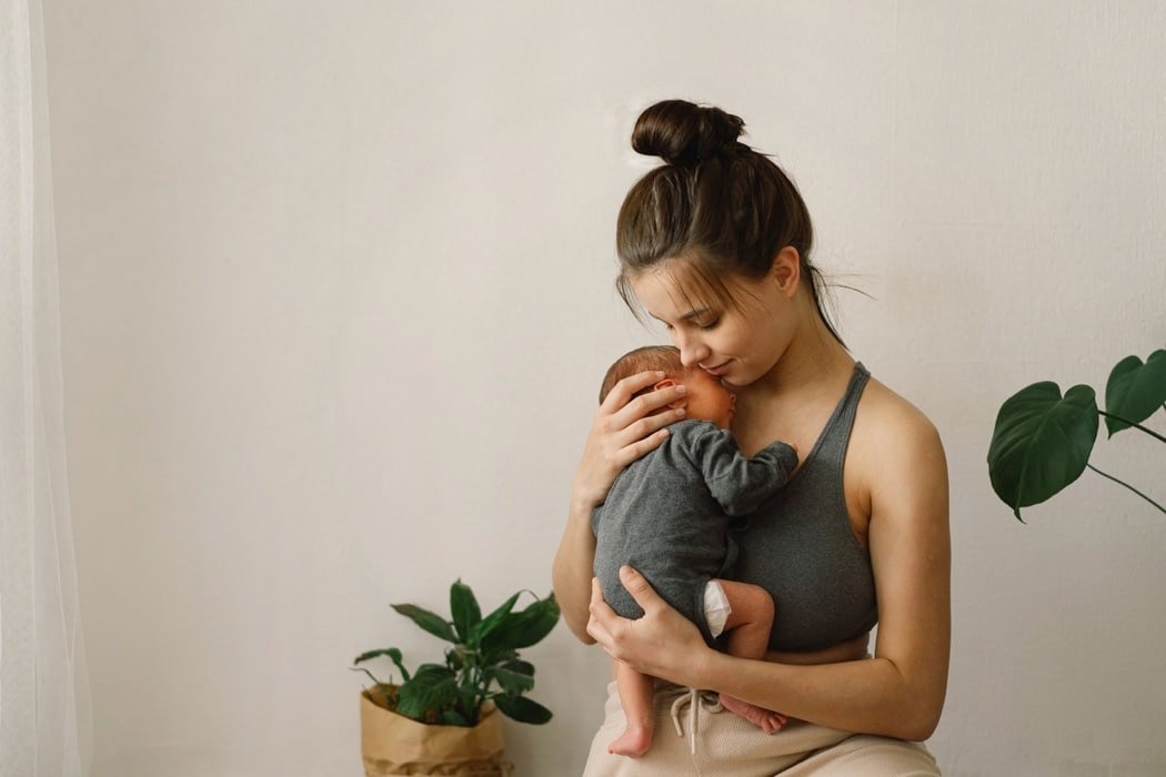 Mother holds and hugs her newborn baby son at home